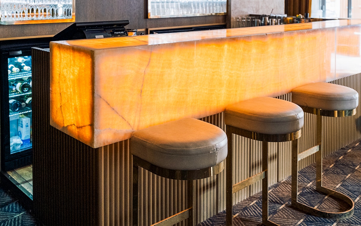 Bar area at Crazy Horse Paris Show and Dinner with illuminated counter and stools.