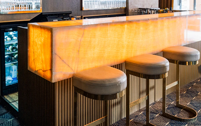 Bar area at Crazy Horse Paris Show and Dinner with illuminated counter and stools.