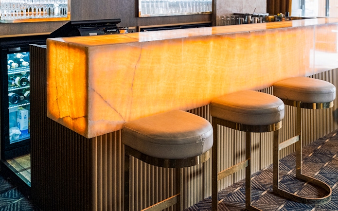 Bar area at Crazy Horse Paris Show and Dinner with illuminated counter and stools.