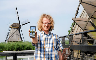Visitor using audio guide at Kinderdijk windmills in the Netherlands.