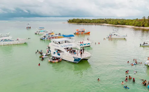 Boat party with snorkeling in the Caribbean Sea near Punta Cana, featuring multiple boats and swimmers.