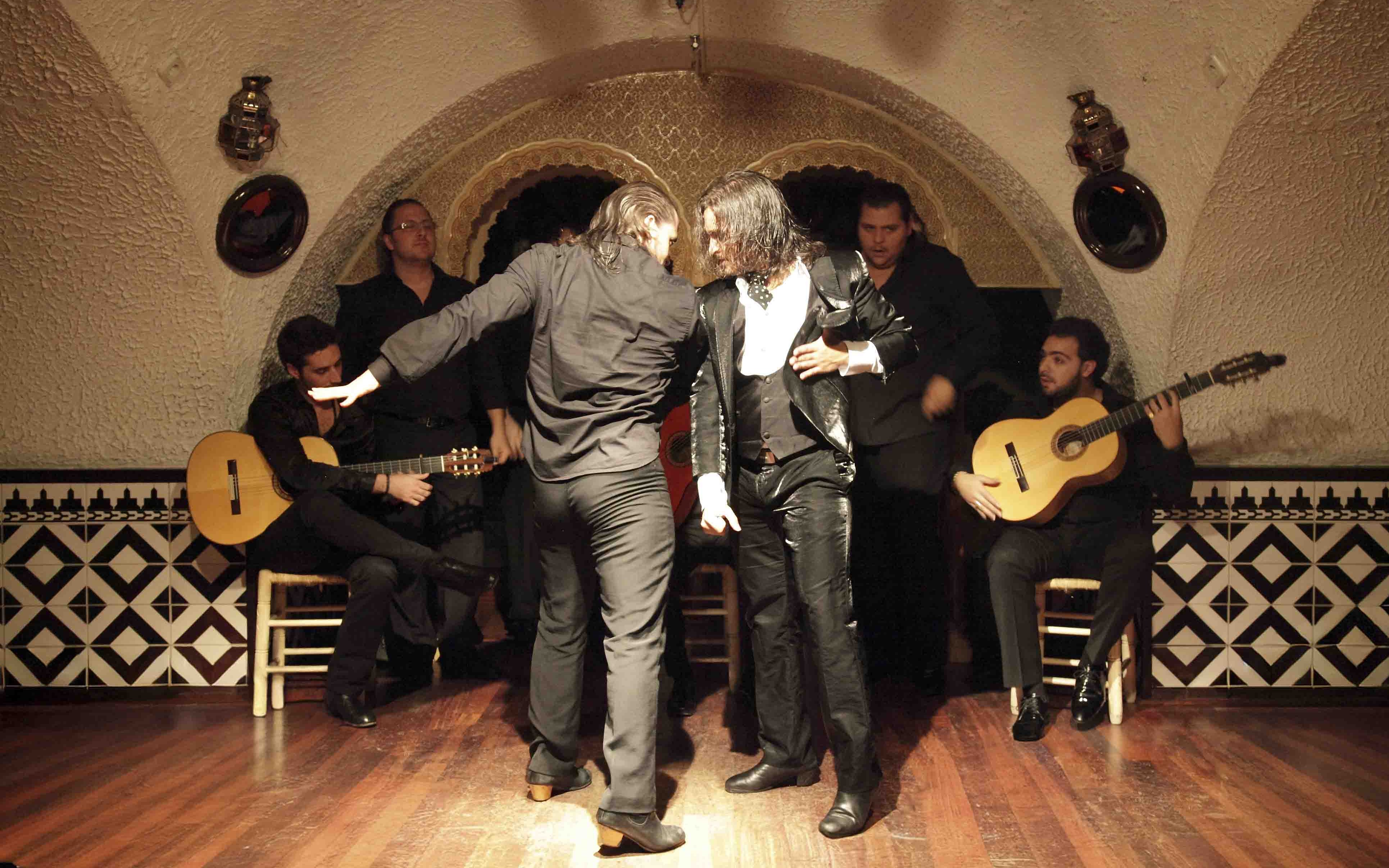 Flamenco dancers performing at Tablao Cordobes with guitarists in the background.