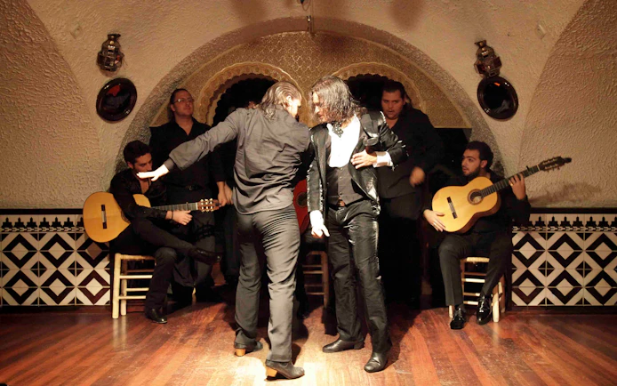 Flamenco dancers performing at Tablao Cordobes with guitarists in the background.