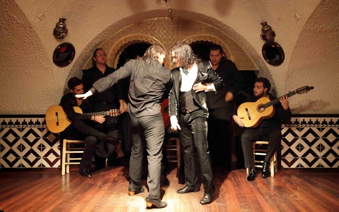 Flamenco dancers performing at Tablao Cordobes with guitarists in the background.