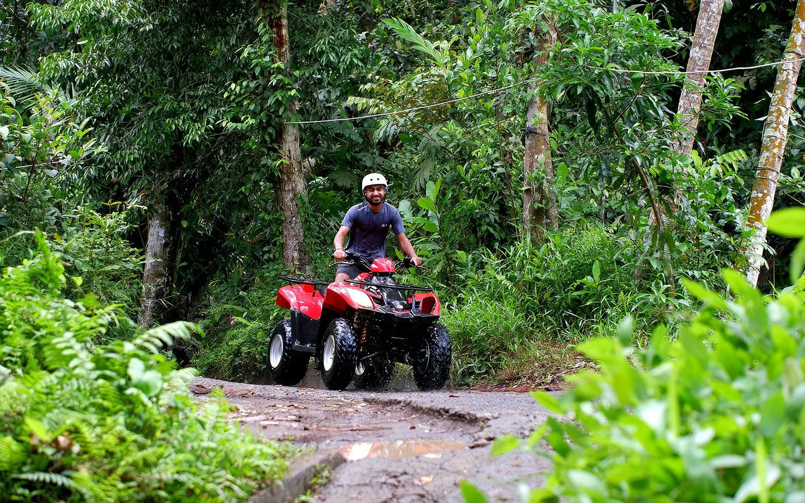 Man riding ATV through lush forest trail in Bali.