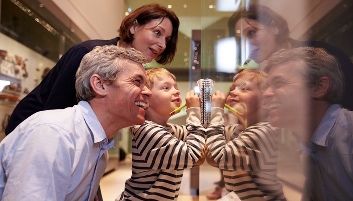 Family with child observing museum artifact through glass display.