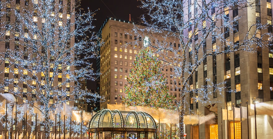 Rockefeller Center Christmas tree with festive lights and surrounding buildings in New York City.