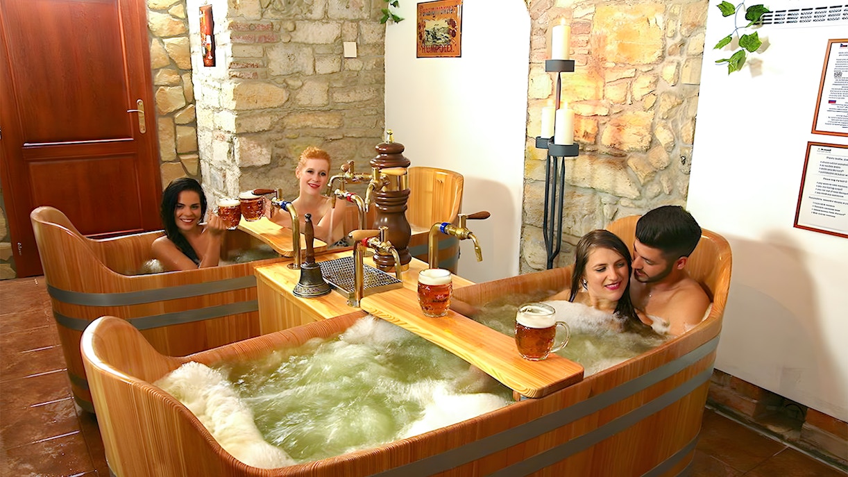 Group of friends at Bernard Beer Spa beer bath experience with wooden tubs in Prague, Czech Republic.