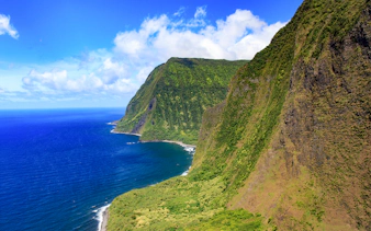 Aerial view of lush cliffs and ocean on a helicopter tour over Maui, Hawaii.