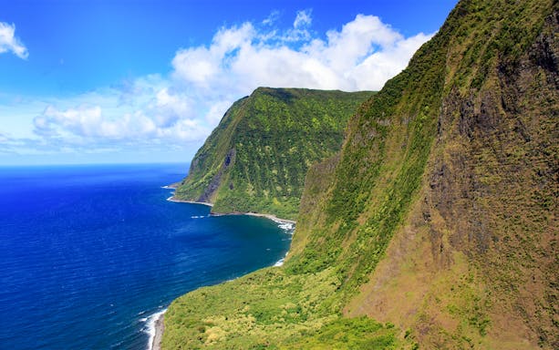 Aerial view of lush cliffs and ocean on a helicopter tour over Maui, Hawaii.