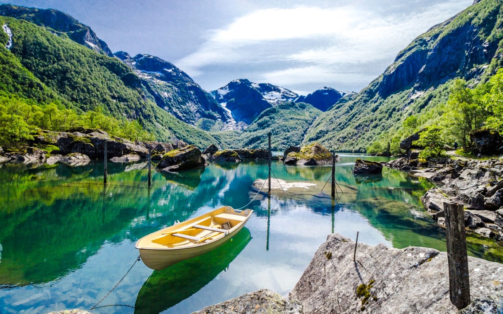 Yellow boat on Bondhus Lake with mountain backdrop in Norway.