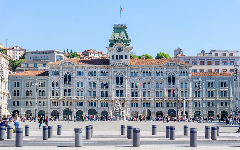 Piazza Unità d'Italia in Trieste with historic government building and people walking.