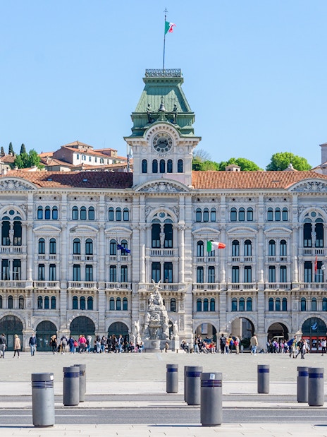 Piazza Unità d'Italia in Trieste with historic government building and people walking.
