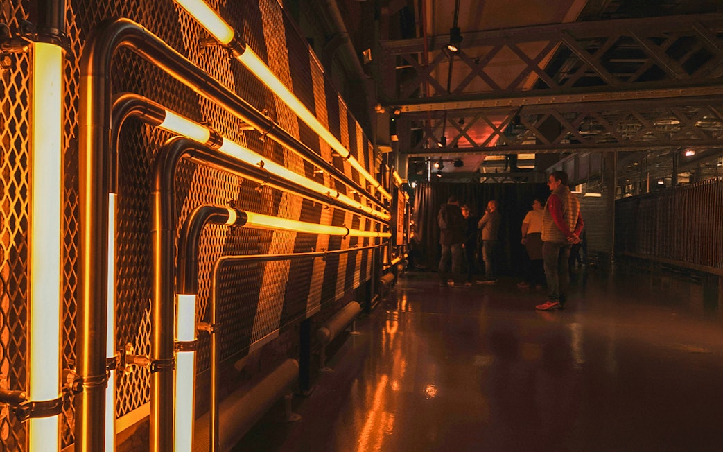 Guinness Storehouse interior with illuminated pipes and visitors exploring.