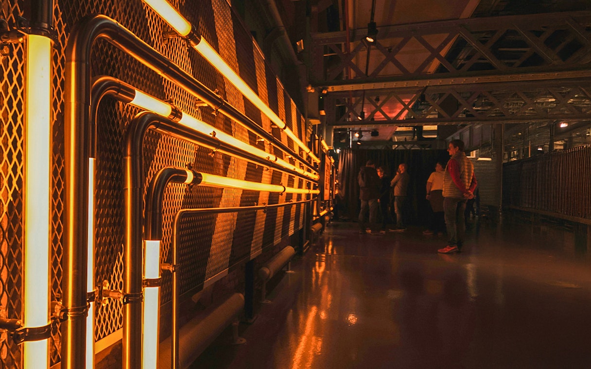 Guinness Storehouse interior with illuminated pipes and visitors exploring.