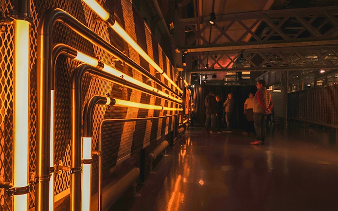 Guinness Storehouse interior with illuminated pipes and visitors exploring.