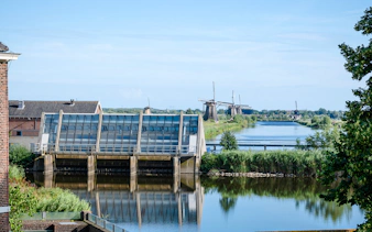 Old Wisboom pumping station with Kinderdijk windmills in the background, Netherlands.