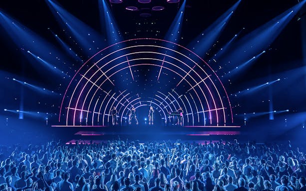 Crowd enjoying ABBA Voyage concert with vibrant stage lights in London.