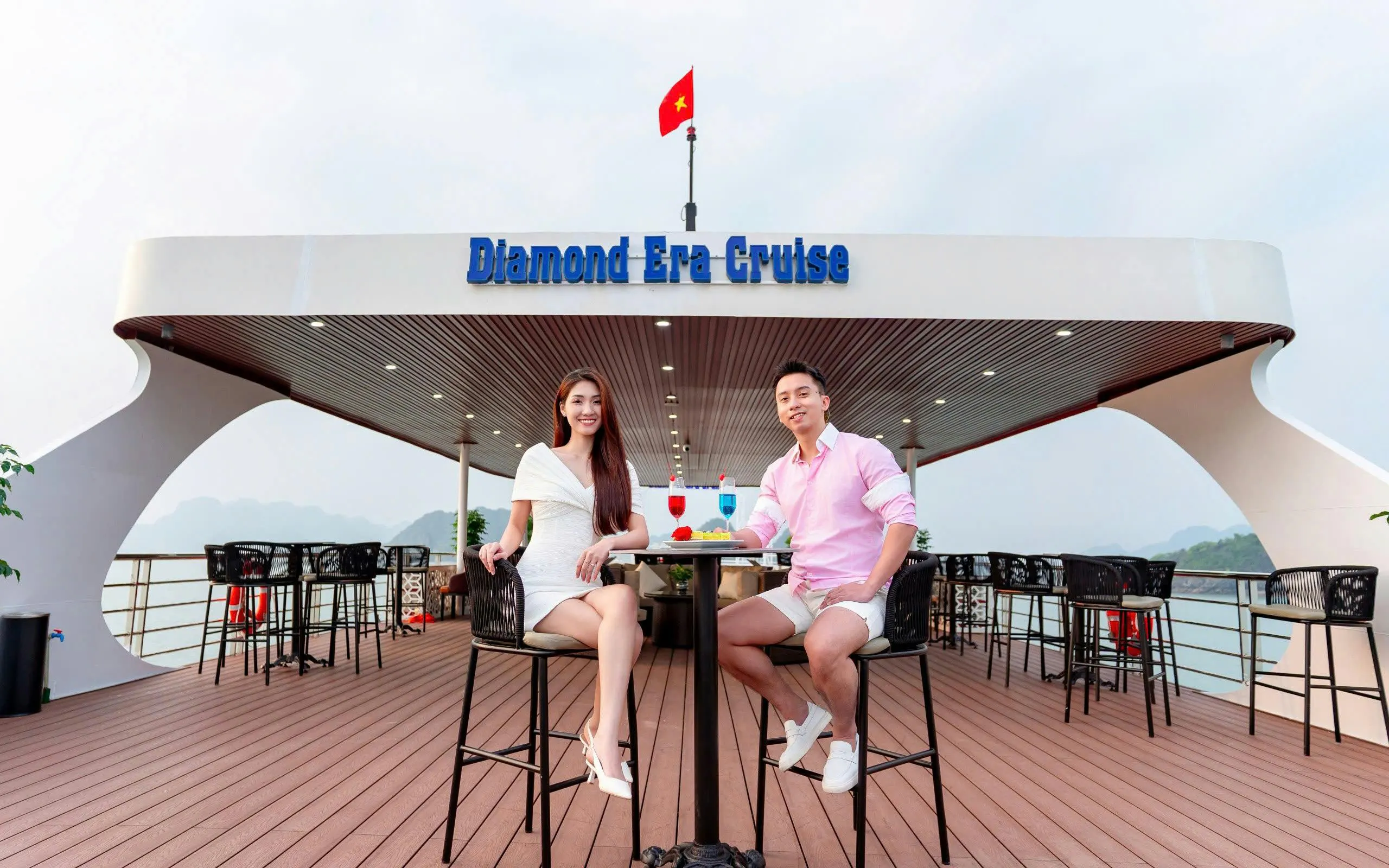 Couple enjoying drinks on the deck of Diamond Era Cruise, Ha Long Bay.