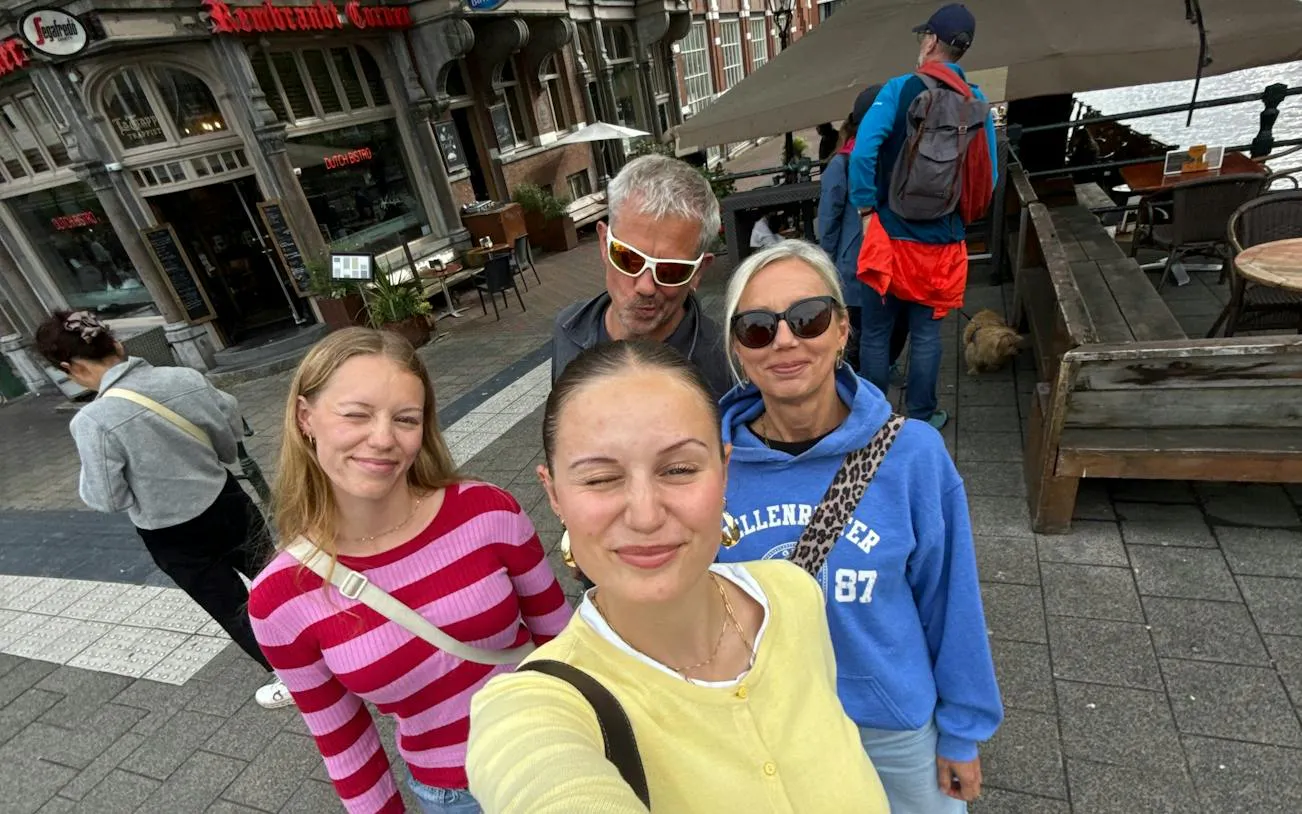 Group enjoying Amsterdam city exploration near Rembrandt-themed cafe.