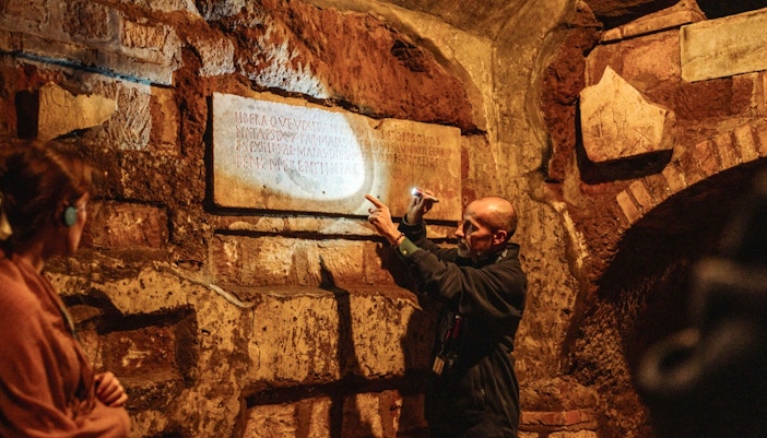 Group of tourists exploring the ancient Roman Catacombs and Capuchin Crypts on a guided tour in Rome, Italy