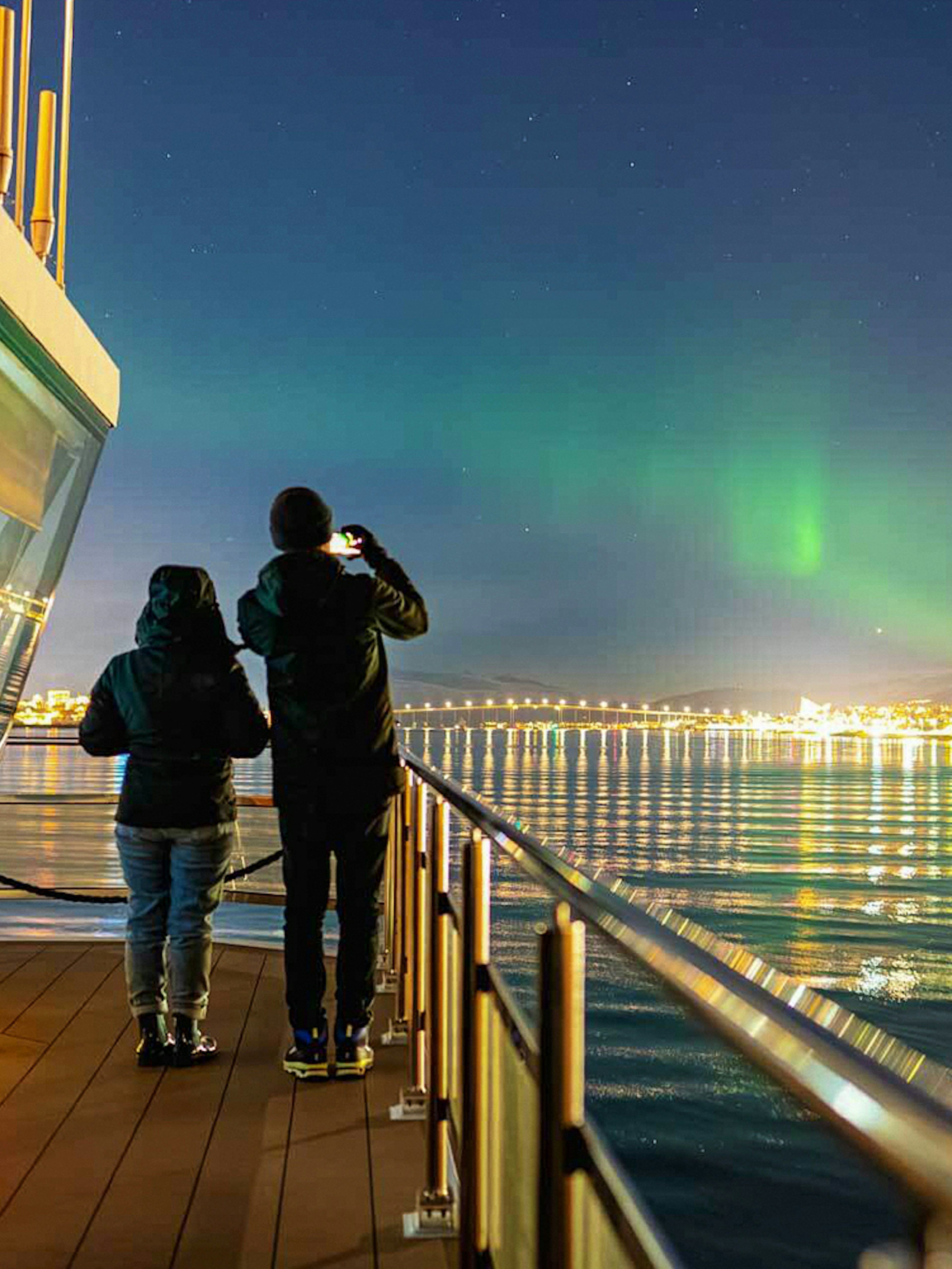 Northern lights over Tromso viewed from a cruise ship deck.