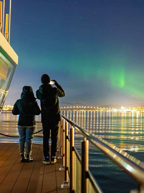 Northern lights over Tromso viewed from a cruise ship deck.