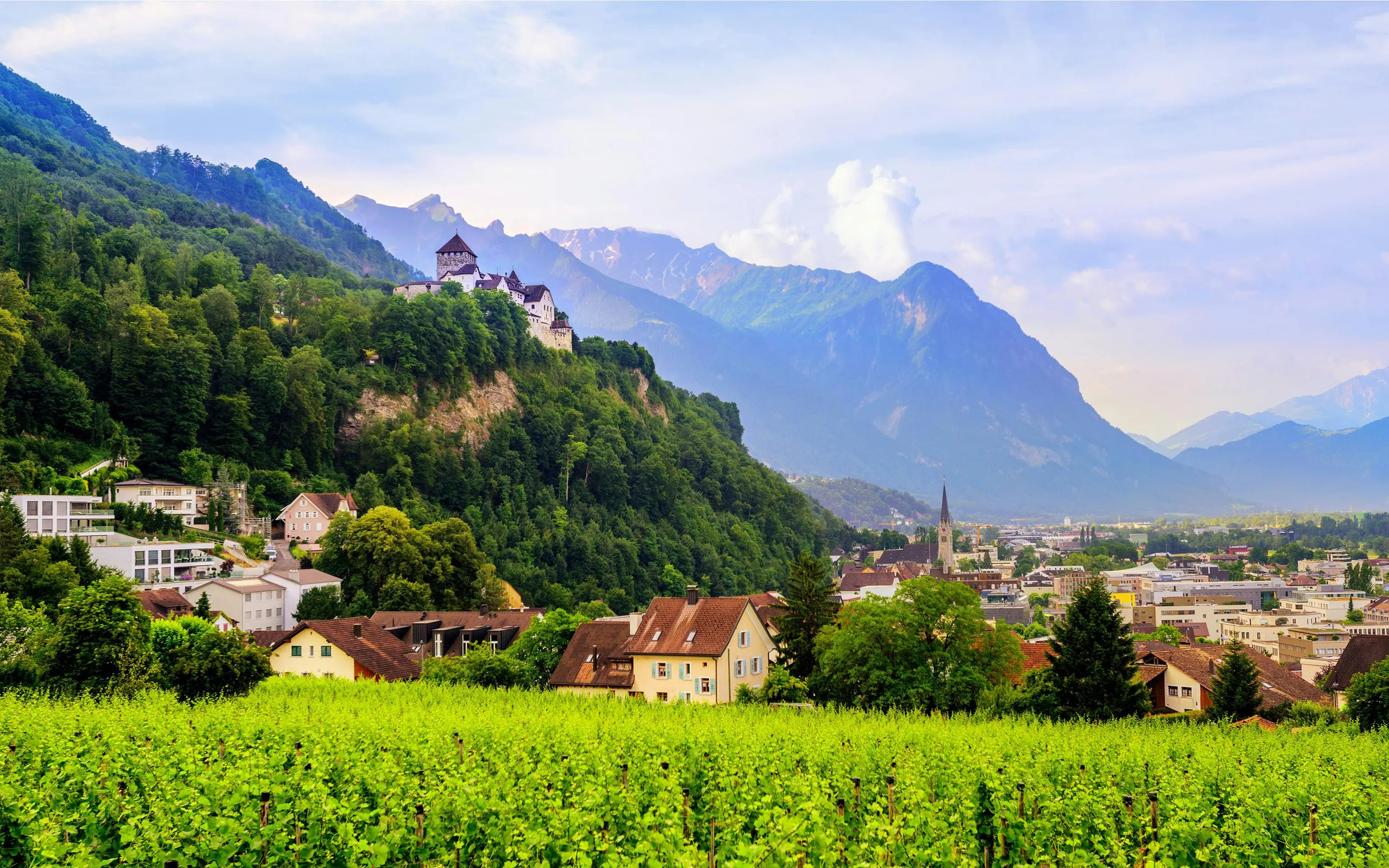 Vaduz Castle overlooking the town of Vaduz, Liechtenstein, with mountains in the background.