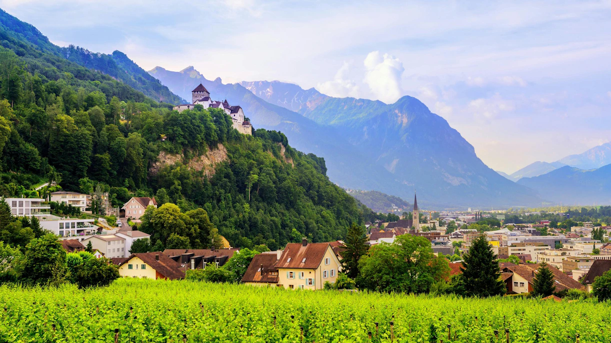 Vaduz Castle overlooking the town of Vaduz, Liechtenstein, with mountains in the background.