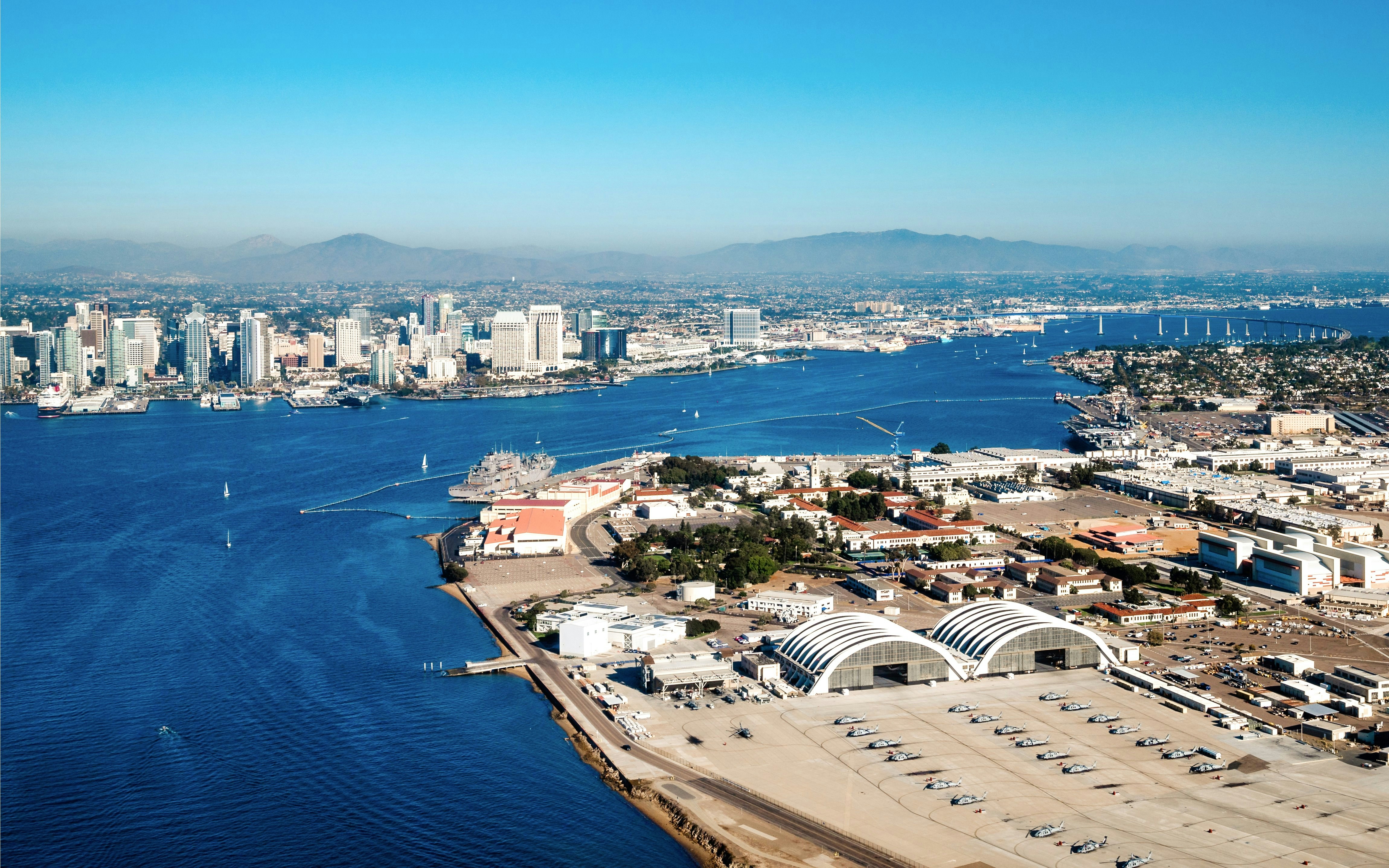 Aerial view of North Island Naval Air Base with San Diego skyline in the background.