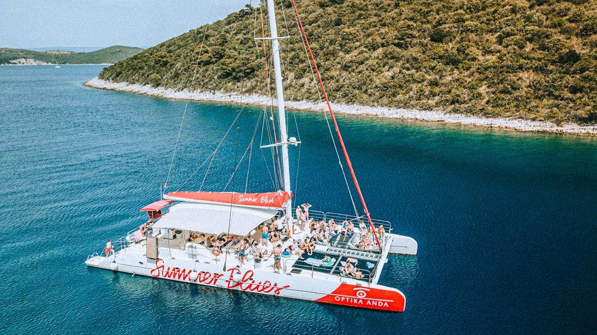 Catamaran with tourists cruising near Hvar and Pakleni Islands, Croatia.