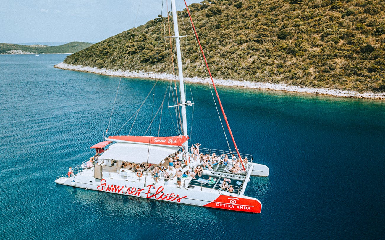 Catamaran with tourists cruising near Hvar and Pakleni Islands, Croatia.