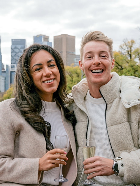 Couple enjoying champagne on a Melbourne brunch cruise with city skyline in background.