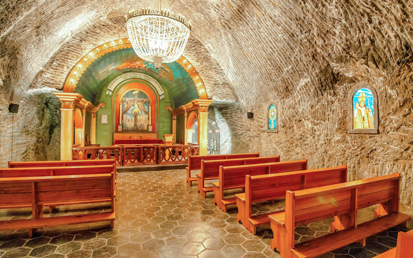 Wieliczka Salt Mine chapel interior with wooden benches and ornate altar.