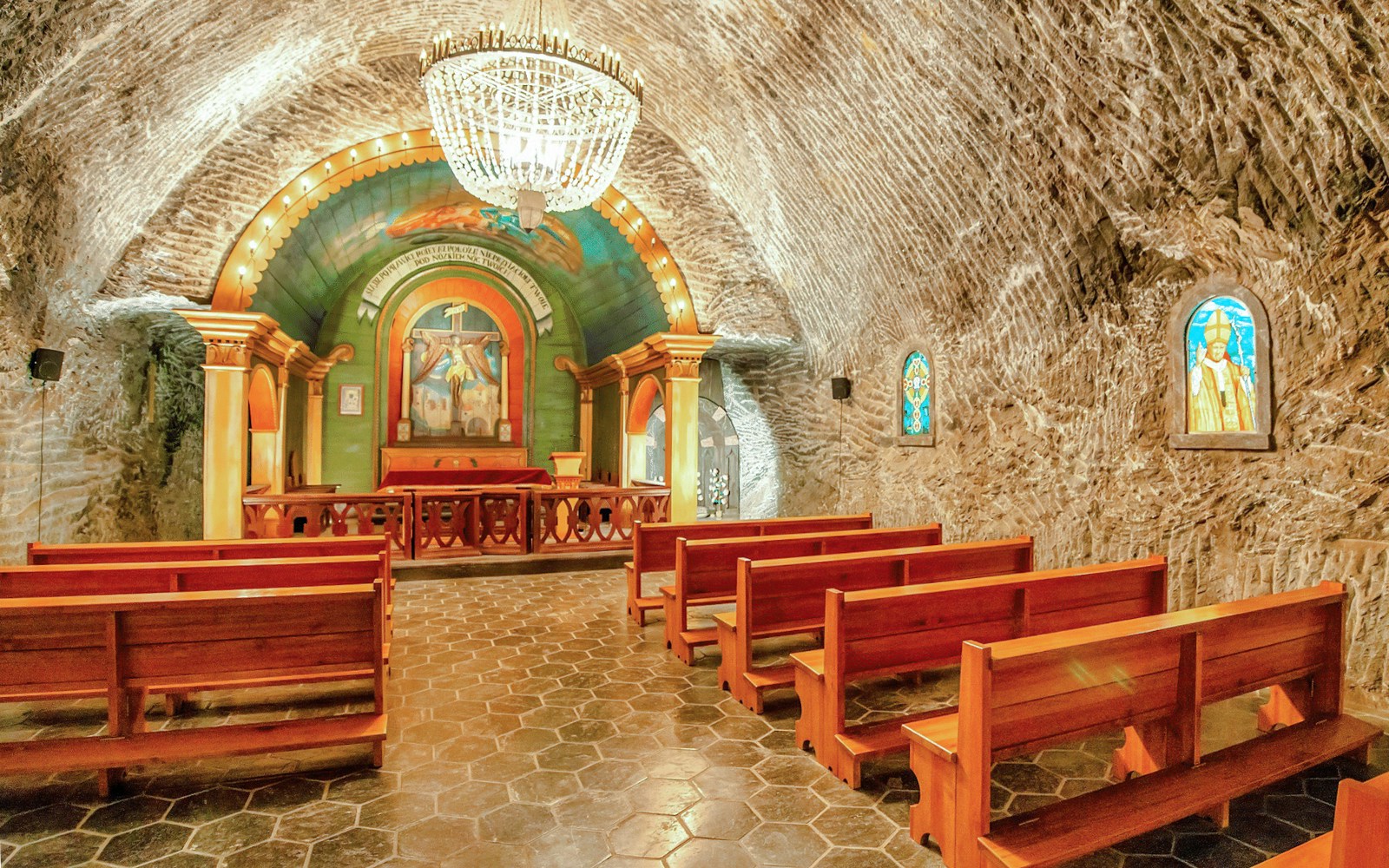Wieliczka Salt Mine chapel interior with wooden benches and ornate altar.