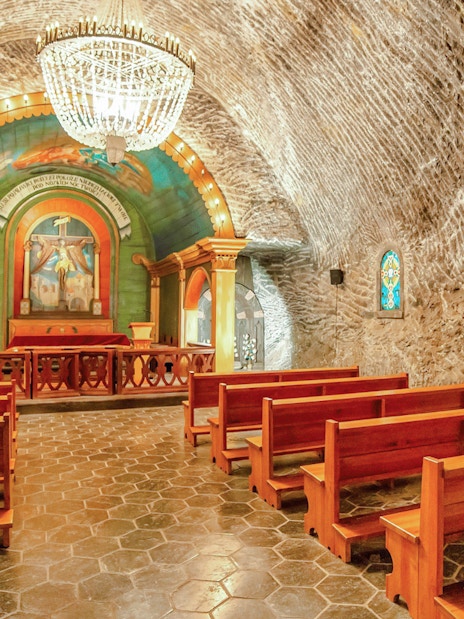 Wieliczka Salt Mine chapel interior with wooden benches and ornate altar.