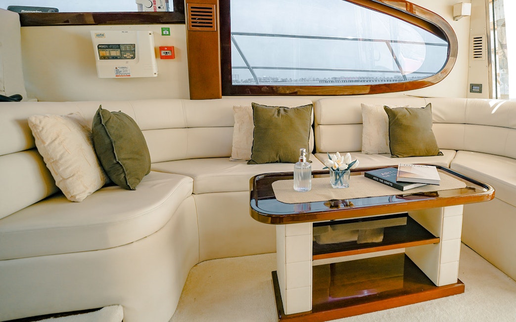 Interior seating area of luxury yacht with table and cushions, Dubai.