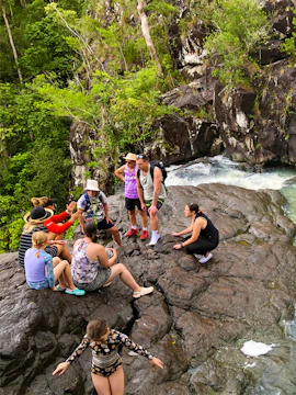 Visitors gathered on rocks near Cedar Creek Falls, surrounded by lush greenery.
