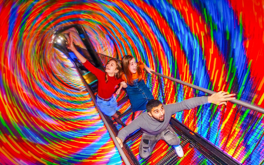 Visitors experiencing the colorful Vortex Tunnel at Camera Obscura & World of Illusions, Edinburgh.