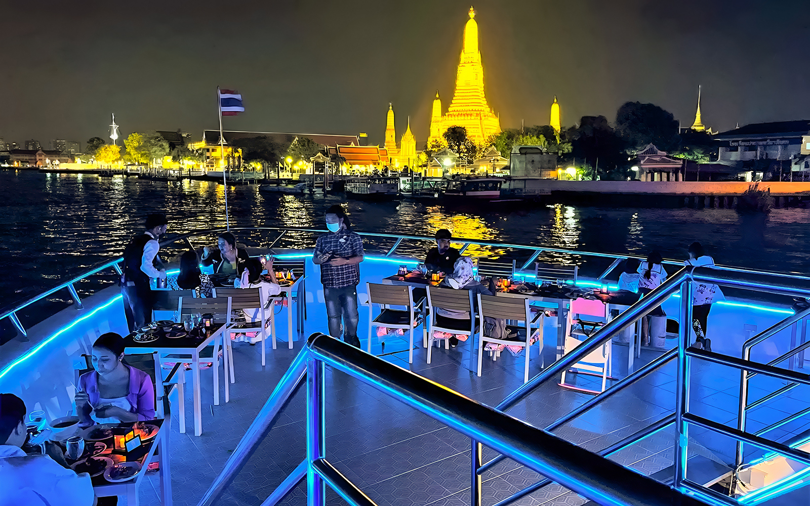 Riverside dinner cruise with buffet and live performances near illuminated Wat Arun, Bangkok.