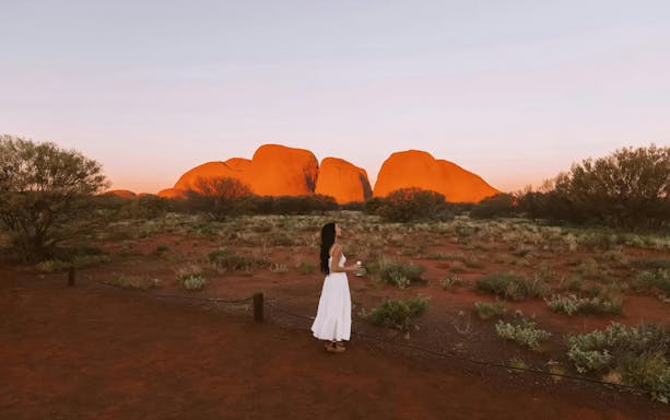 Woman standing in front of Kata Tjuta rock formations at sunset, Uluru-Kata Tjuta National Park.