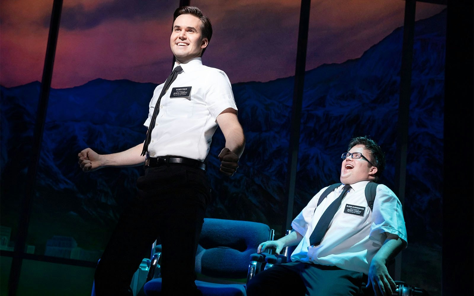 Stage scene from The Book of Mormon Broadway show with two actors in white shirts.