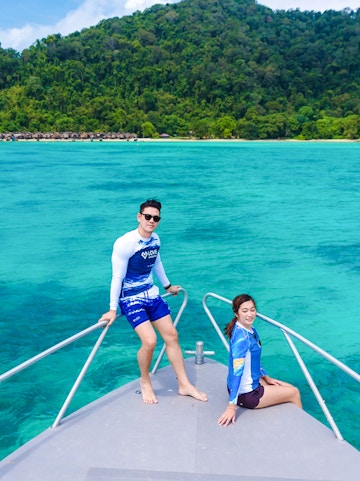 Couple on speedboat bow with Surin Islands' turquoise waters in background.