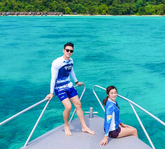 Couple on speedboat bow with Surin Islands' turquoise waters in background.