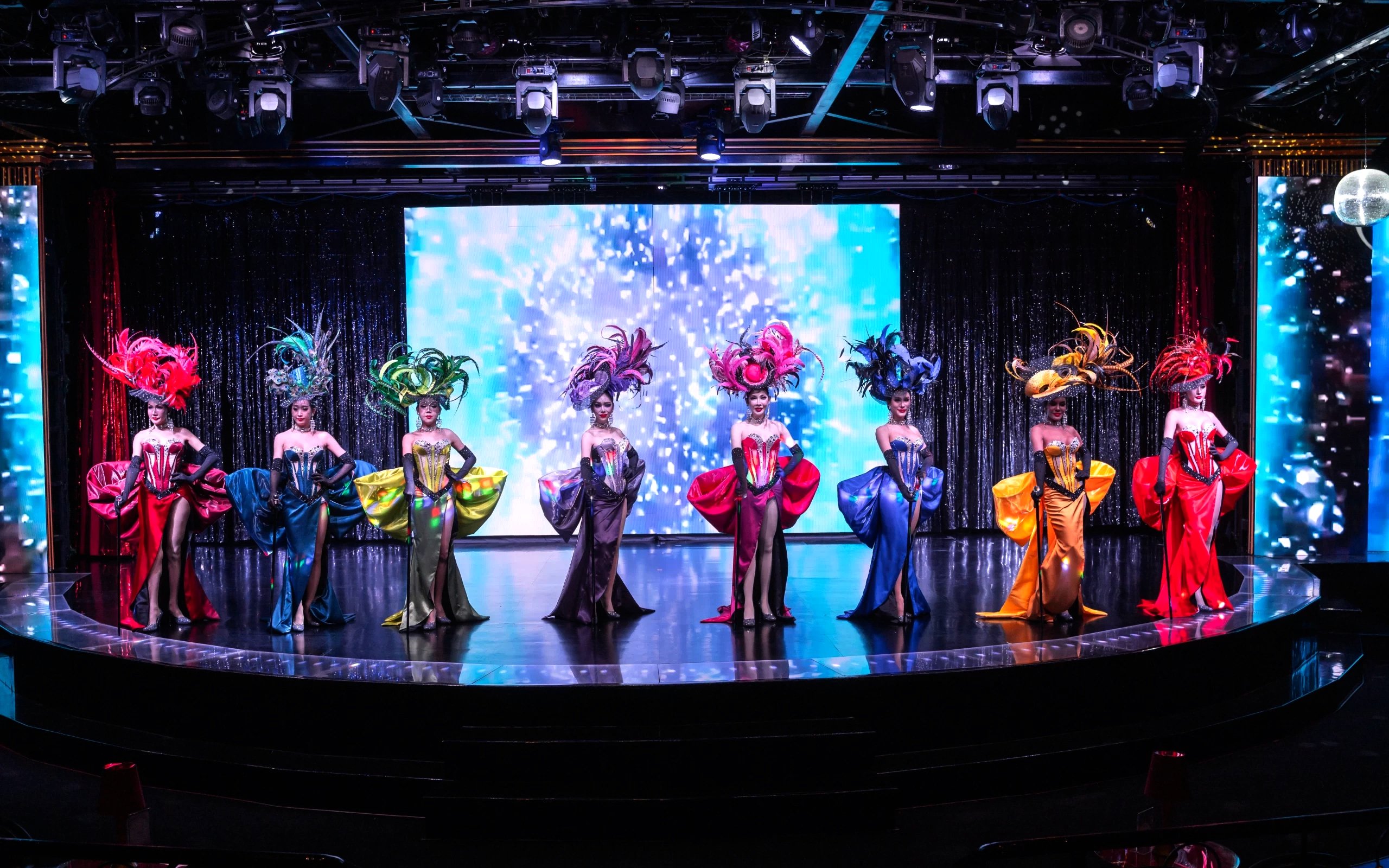 Performers in vibrant costumes on stage at Calypso Cabaret, Bangkok.