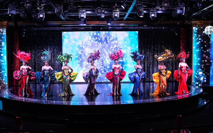 Performers in vibrant costumes on stage at Calypso Cabaret, Bangkok.