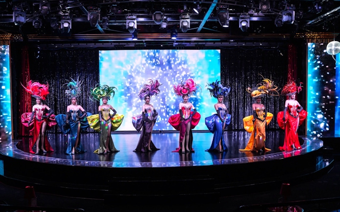 Performers in vibrant costumes on stage at Calypso Cabaret, Bangkok.
