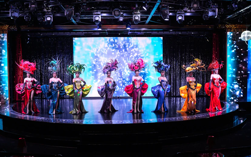 Performers in vibrant costumes on stage at Calypso Cabaret, Bangkok.