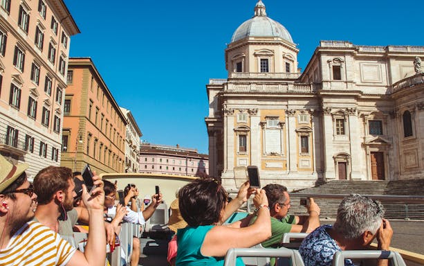 Tourists on an open-top Big Bus Tours Rome passing the Colosseum in Rome, Italy.