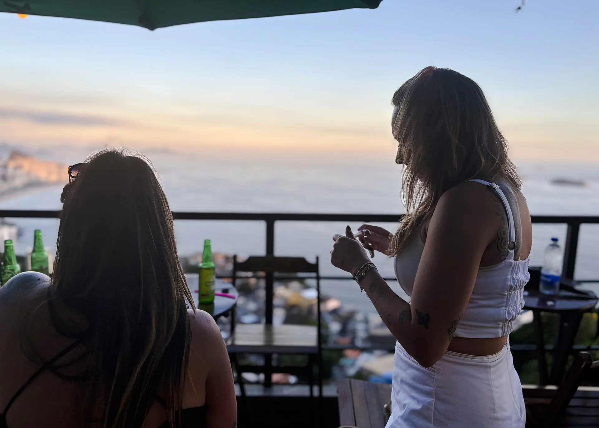 Women enjoying drinks with ocean view from Vidigal, Rio de Janeiro.
